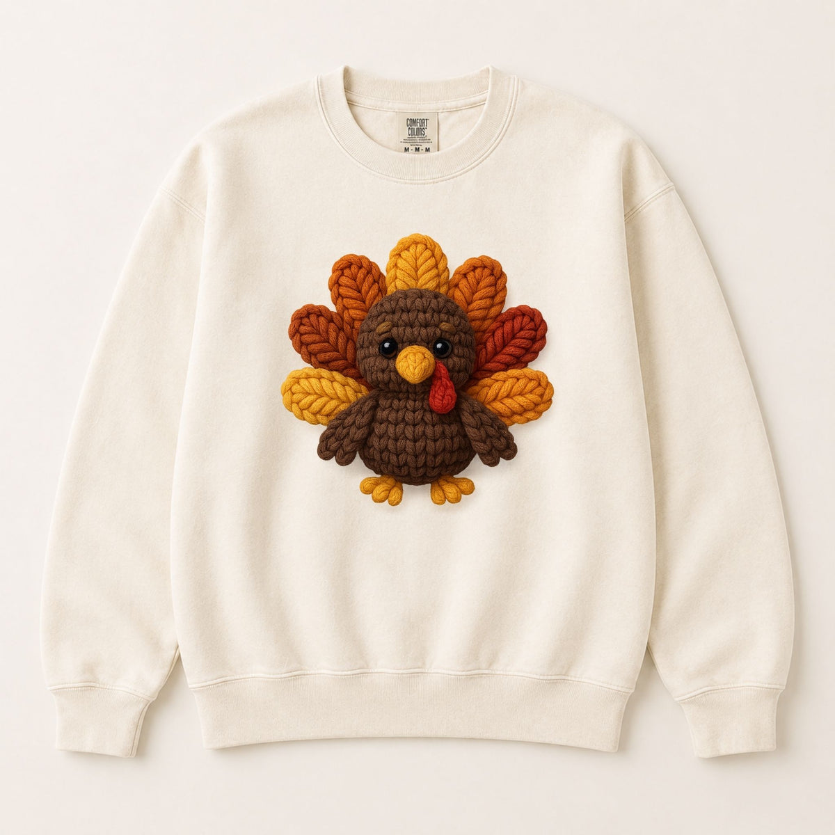 Cream crewneck sweatshirt laid flat with centered knitted turkey face graphic.