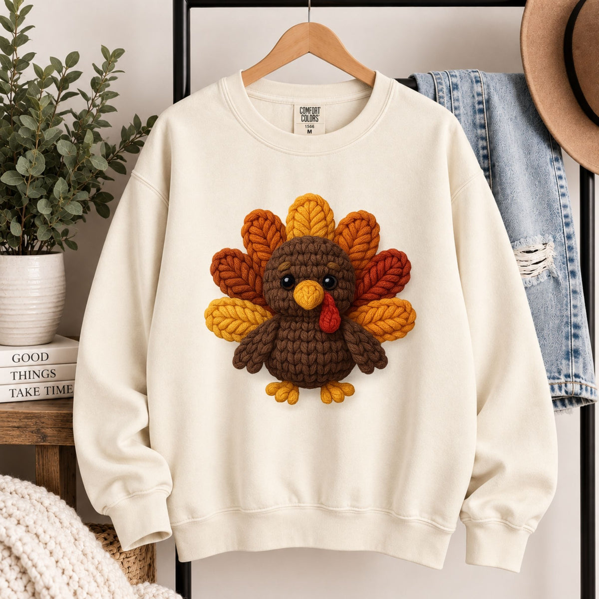 Cream sweatshirt on a hanger with knitted turkey appliqué at the center.