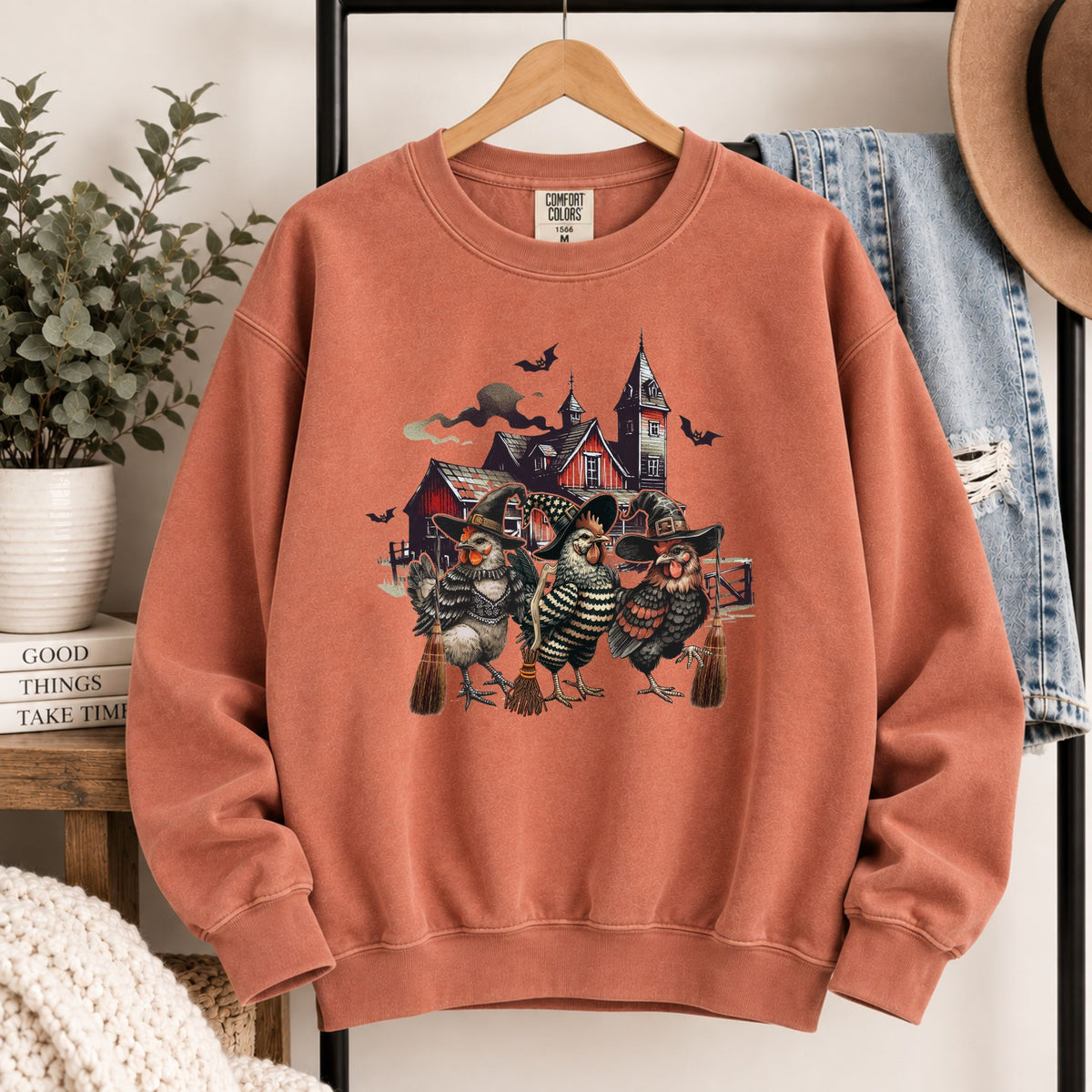 Rust-orange crewneck sweatshirt with witchy chicken and haunted house front design