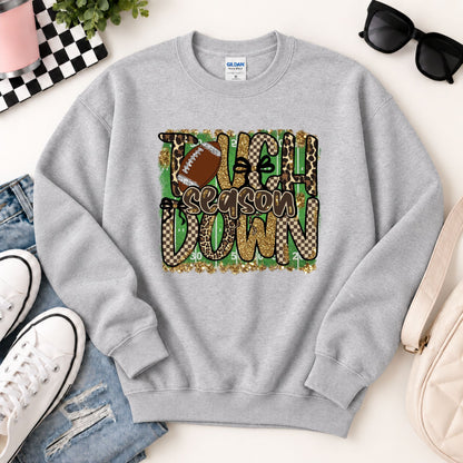 Light gray sweatshirt flat lay with “Touchdown Season” leopard camo football graphic.