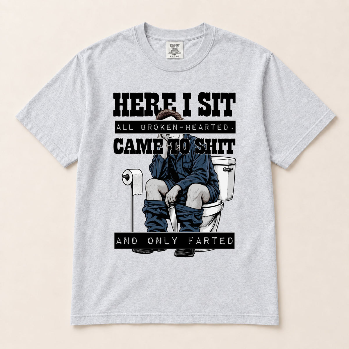 Light gray graphic short-sleeve tee with “HERE I SIT” toilet gag illustration centered.