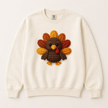 Cream crewneck sweatshirt laid flat with centered knitted turkey face graphic.