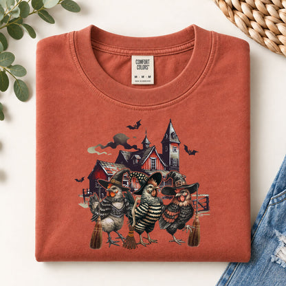 Rust-orange sweatshirt flat lay with witchy chicken and spooky house front graphic