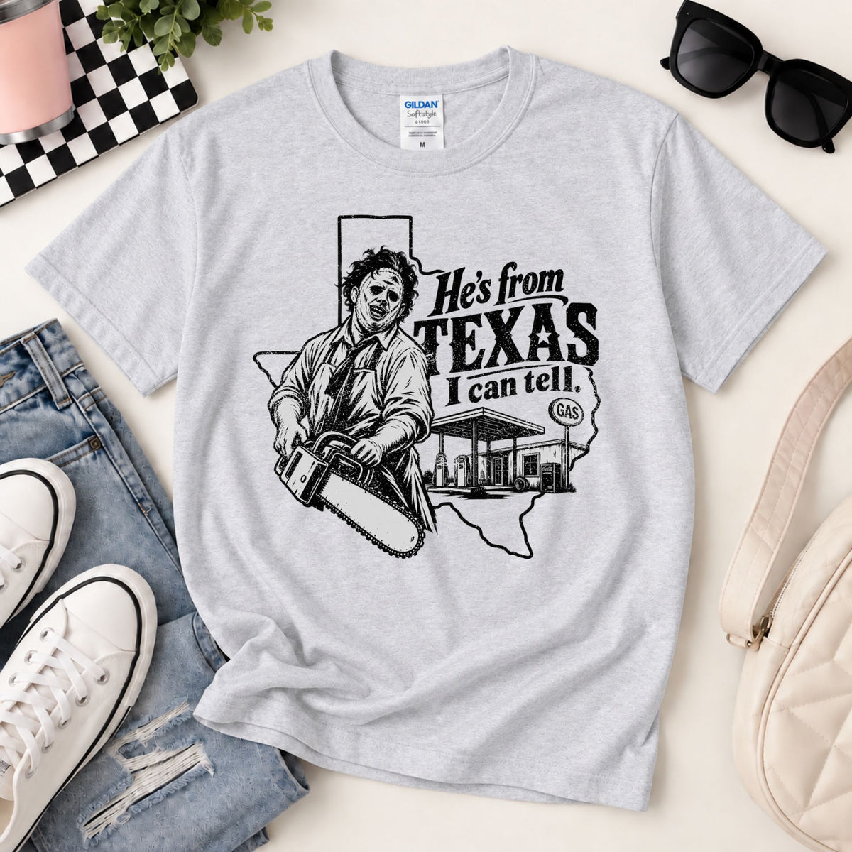 Light heather gray horror graphic T-shirt laid flat with chainsaw Texas text print