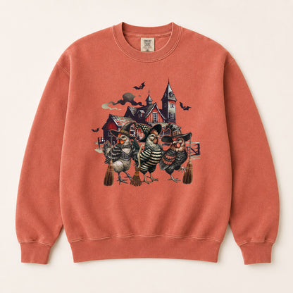 Rust-orange sweatshirt with witchy chicken and spooky house graphic, crewneck front