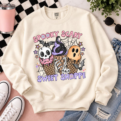 Cream Halloween sweatshirt laid flat with skull, web, and ice-cream graphic