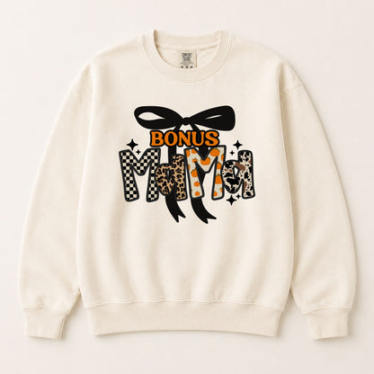 Cream crewneck sweatshirt with yellow “Bonus” text and fall “Mama” graphic with black bow.