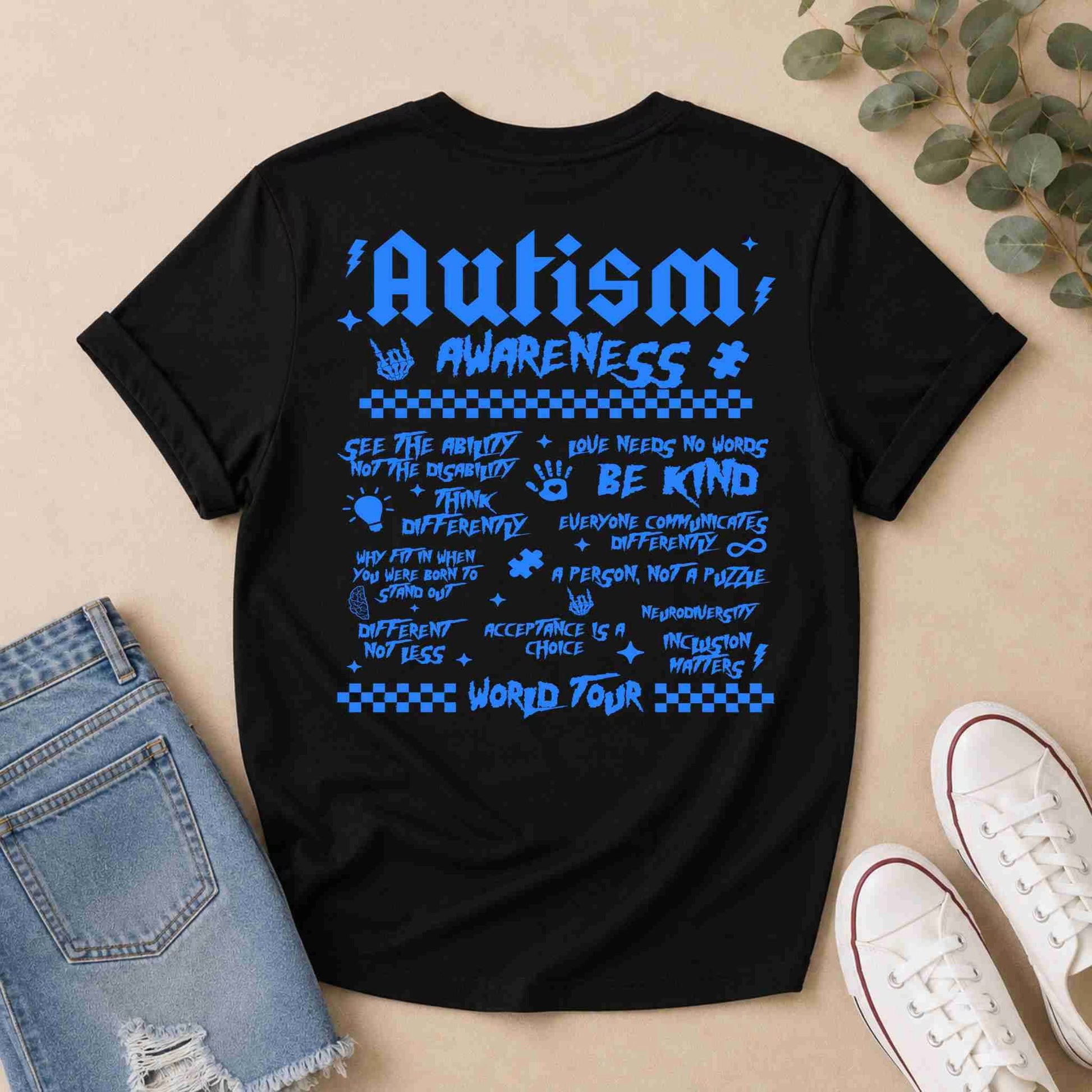 Black t-shirt with Blue 'Autism World Tour' design on a light surface with casual items.