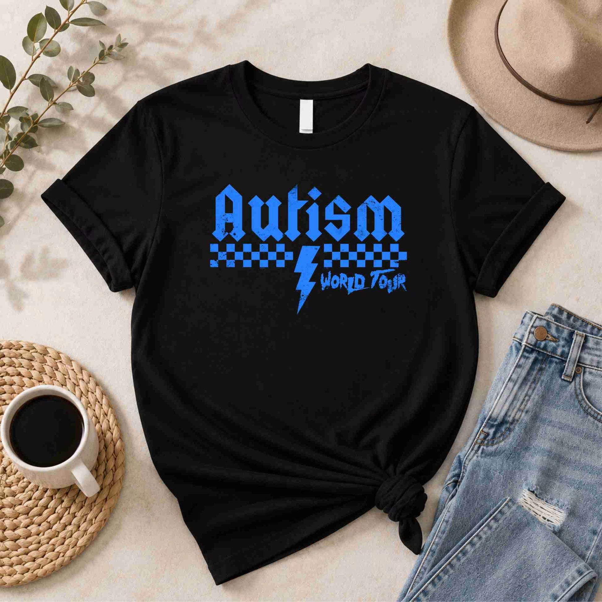 Black t-shirt with Blue 'Autism World Tour' design on a light surface with casual items.