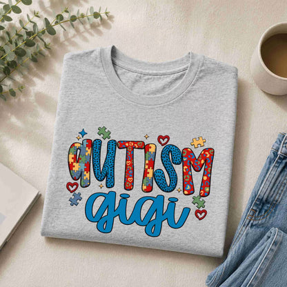 Gray sweatshirt with 'Autism Gigi' text on a light surface with a cup and plant.