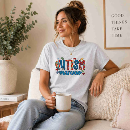 Woman wearing a 'Autism Mamaw' t-shirt, sitting on a couch holding a mug.