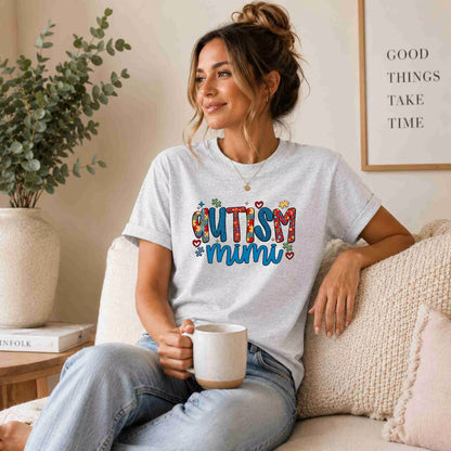 Woman wearing a 'Autism Mimi' t-shirt, sitting on a couch holding a mug.