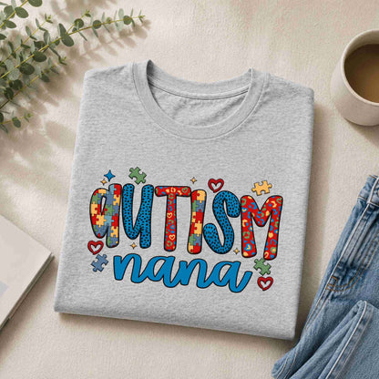 Gray sweatshirt with 'Autism Nana' text on a light surface with a cup and plant.