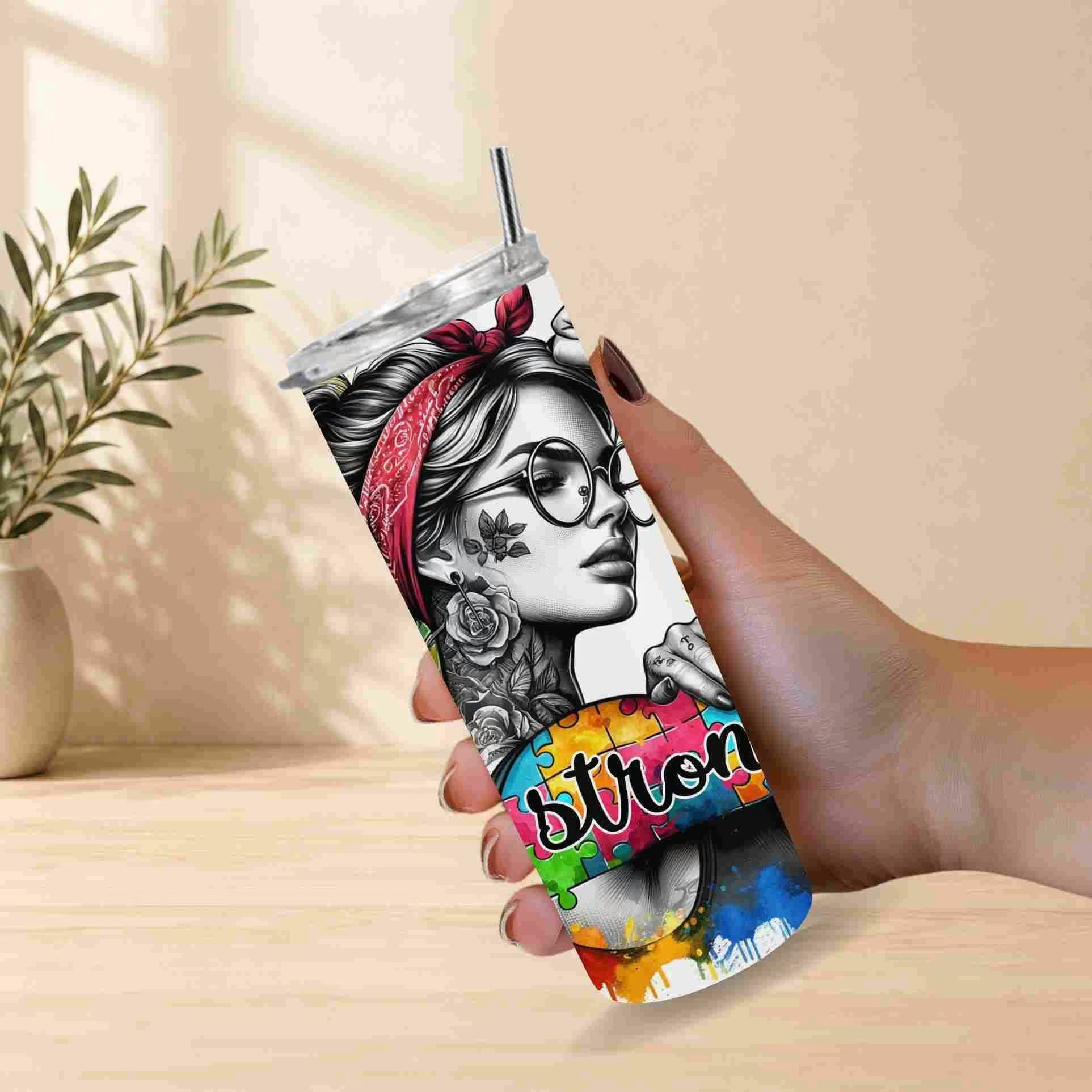 Tumbler with a colorful design of a woman's face held by a hand on a light wooden surface.