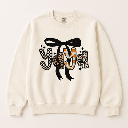 Cream crewneck sweatshirt with black bow and fall letter graphic with orange pumpkin accents.