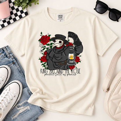 Cream graphic tee on flat lay with plague doctor holding lantern and red rose print