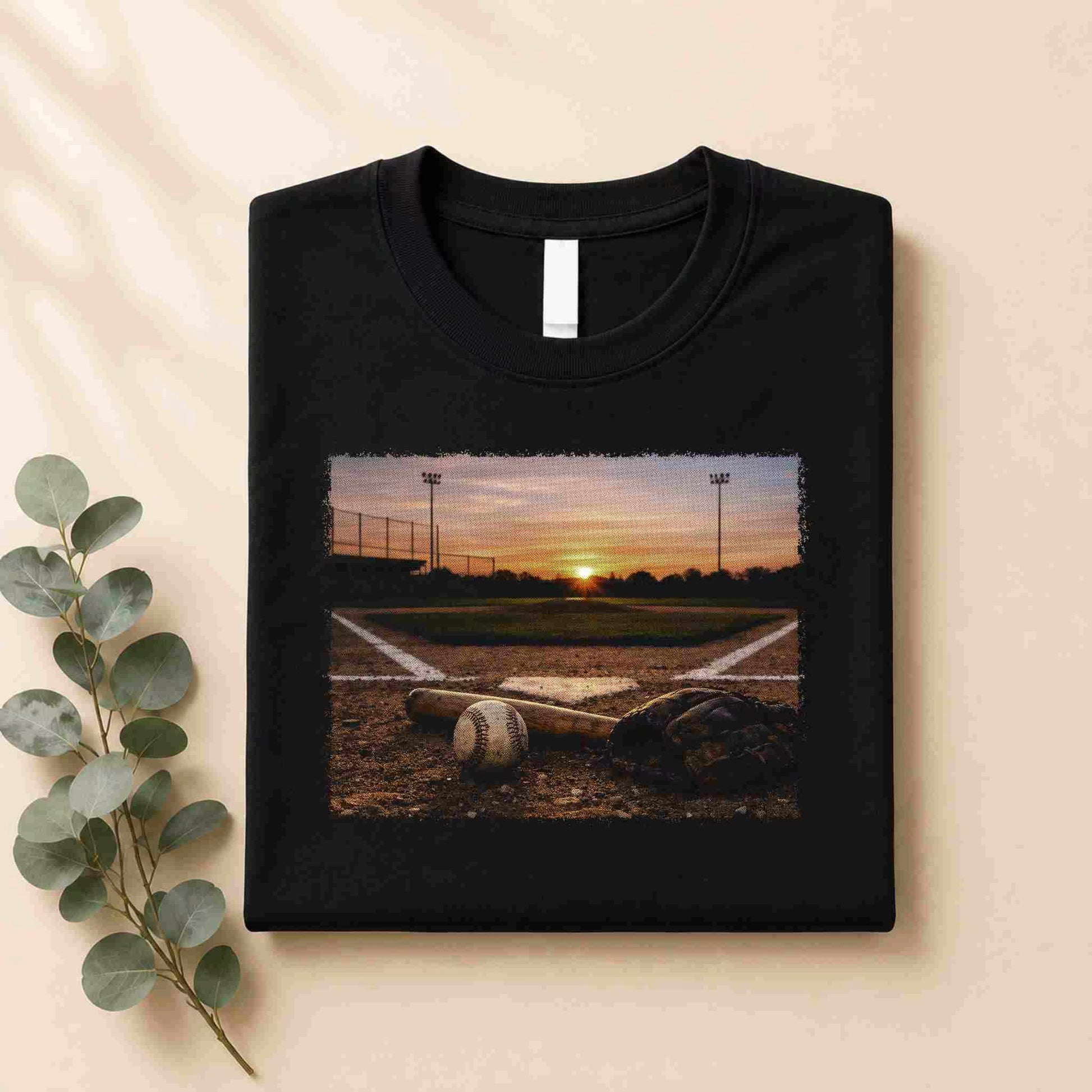 Black t-shirt with a printed design of a baseball field at sunset on a beige background.
