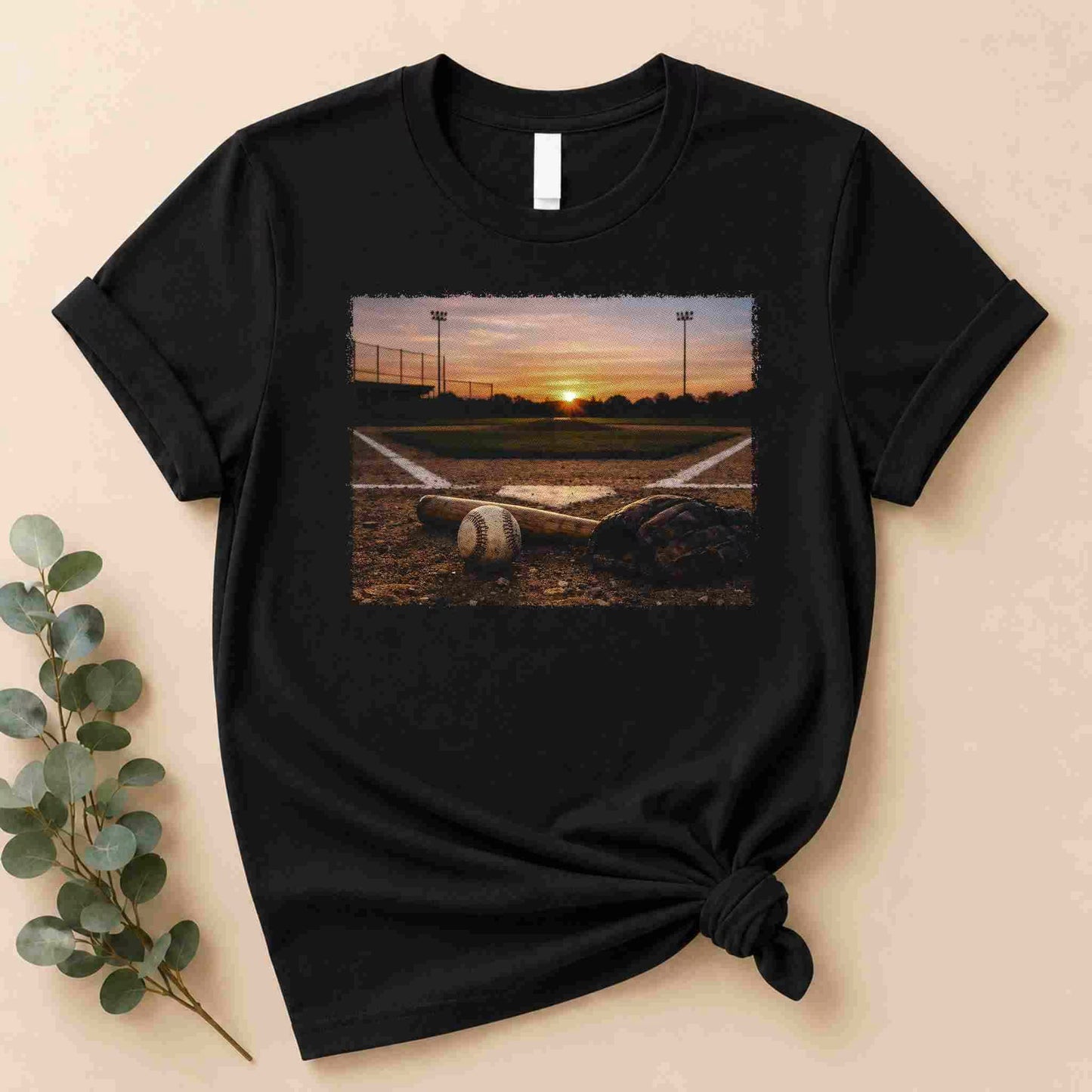 Black t-shirt with a printed design of a sunset over a sports field on a beige background.
