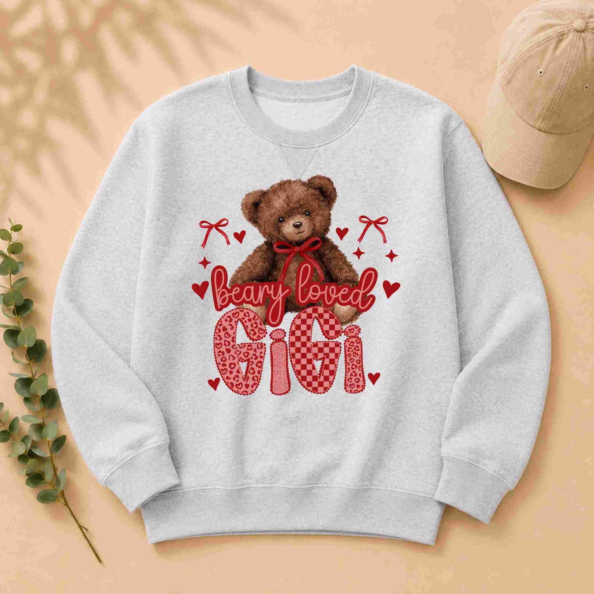 Gray sweatshirt with a teddy bear graphic and 'Beary Loved Gigi' text on a beige background.