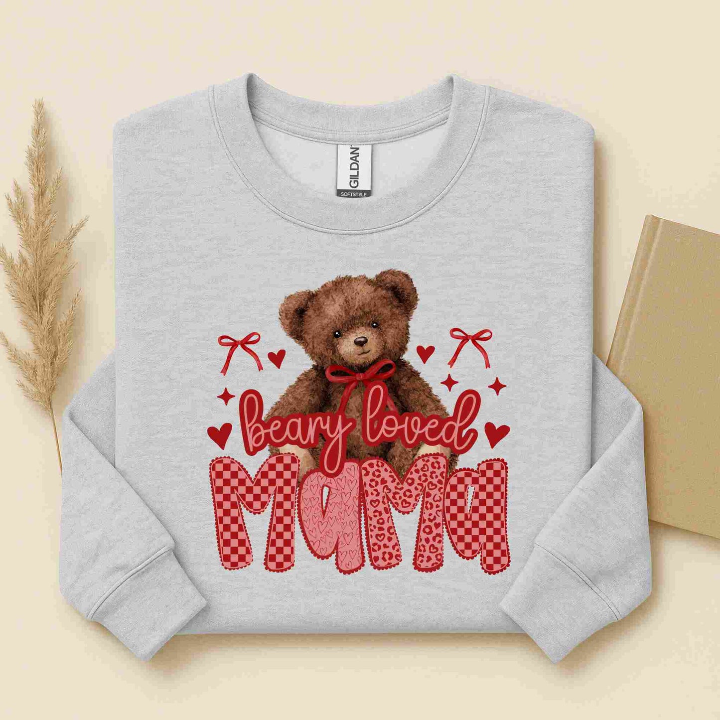 Gray sweatshirt with a teddy bear graphic and 'Beary Loved Mami' text on a beige background