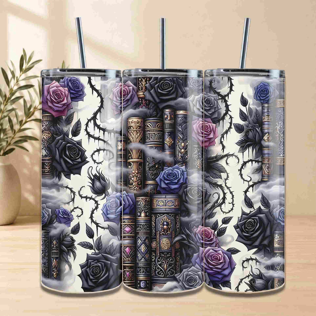 The Dark Book Lover 20oz Skinny Tumbler set by Becca's Banging Designs LLC features three tumblers with vintage books, black and purple roses, thorny vines, and mist—a dreamy gothic look for book lovers. A blurred plant accents the background.