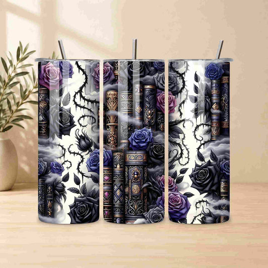The Dark Book Lover 20oz Skinny Tumbler by Becca's Banging Designs LLC features ornate books, black and purple roses, thorny vines, and swirling mist—perfect for gothic book lovers. Stainless steel straw included. Blurred plant in background.