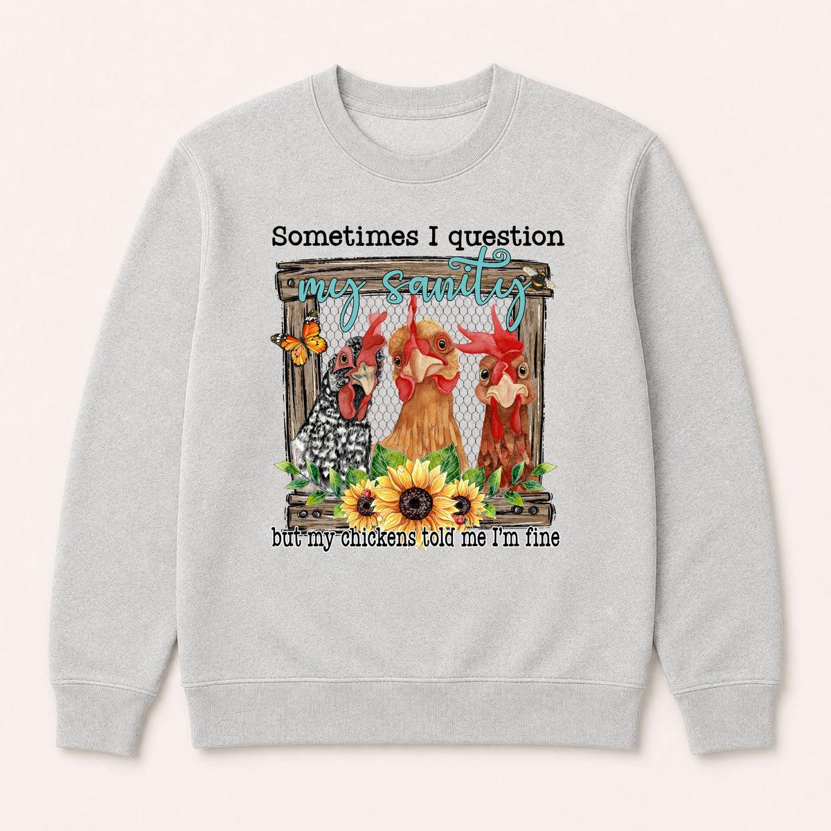 Light grey crewneck sweatshirt with front chicken graphic and quote text, flat lay.