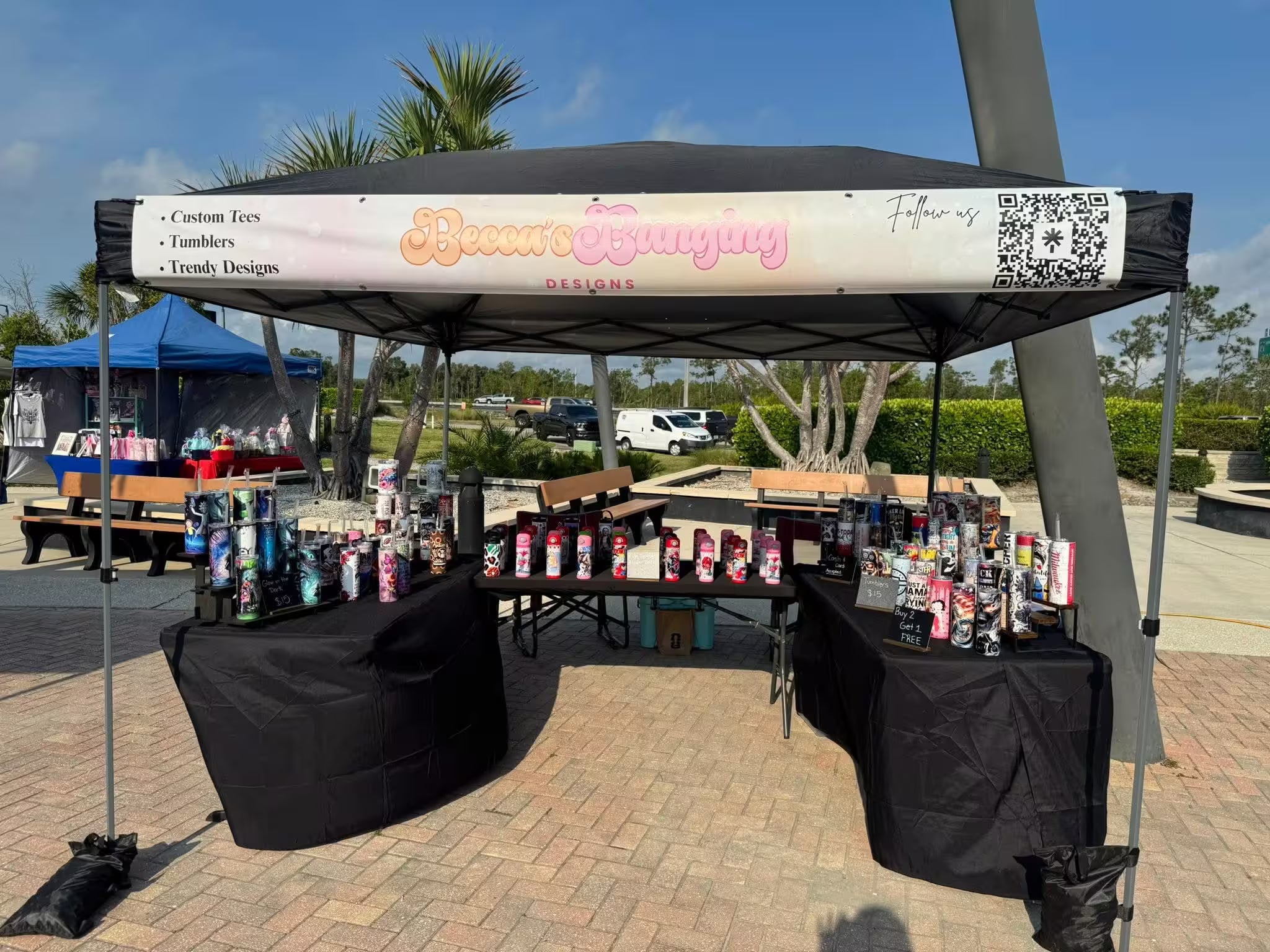 Outdoor event with a booth displaying merchandise under a branded canopy.