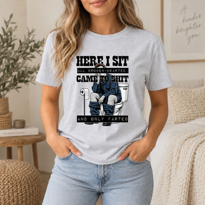 Light gray graphic crew t-shirt with toilet gag print and dark “HERE I SIT” lettering.