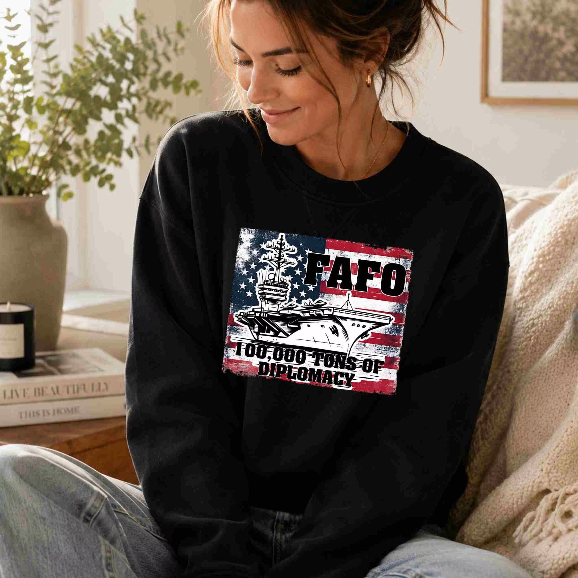 Woman wearing a black sweatshirt with a graphic design sitting on a couch.