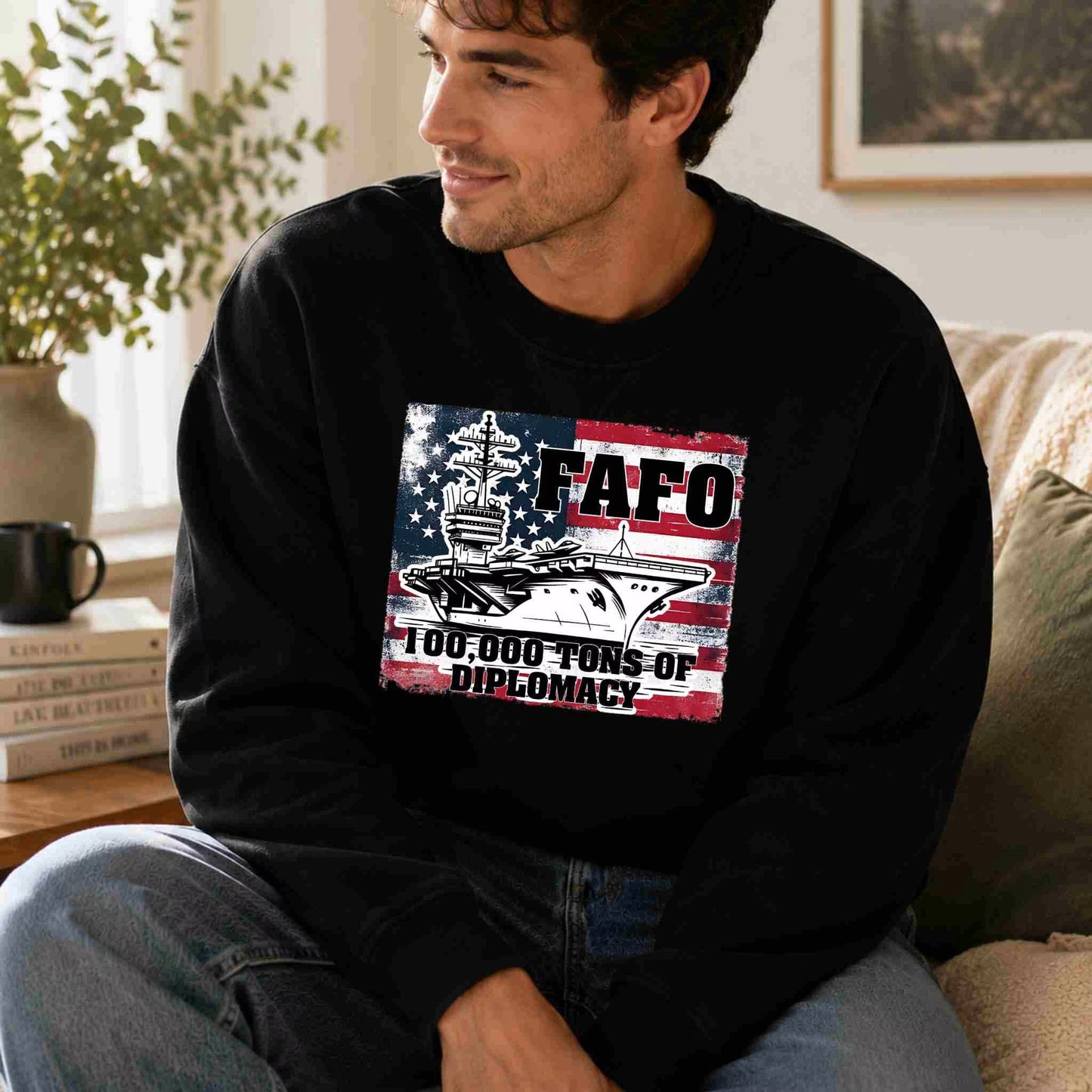 Man wearing a black sweatshirt with a graphic design sitting on a couch.