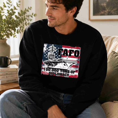Man wearing a black sweatshirt with a graphic design sitting on a couch.
