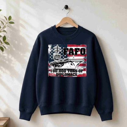 Navy blue sweatshirt with graphic design and text on a hanger against a white wall.