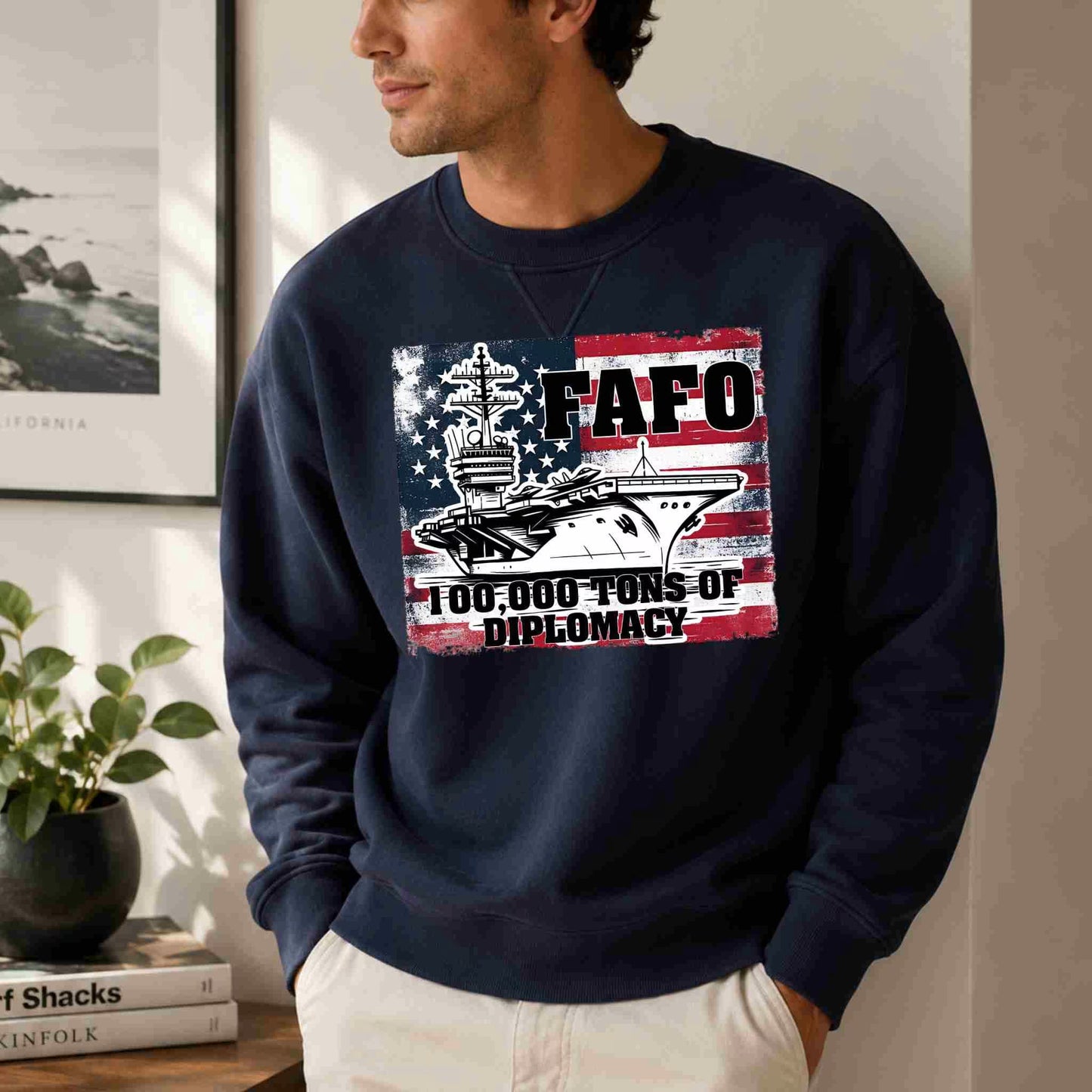 Man wearing a navy blue sweatshirt with a graphic design and text, standing indoors.