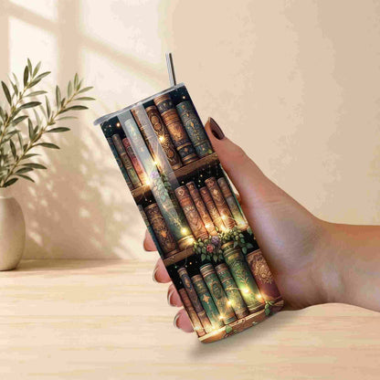 Tumbler with book design held by a hand on a light surface.