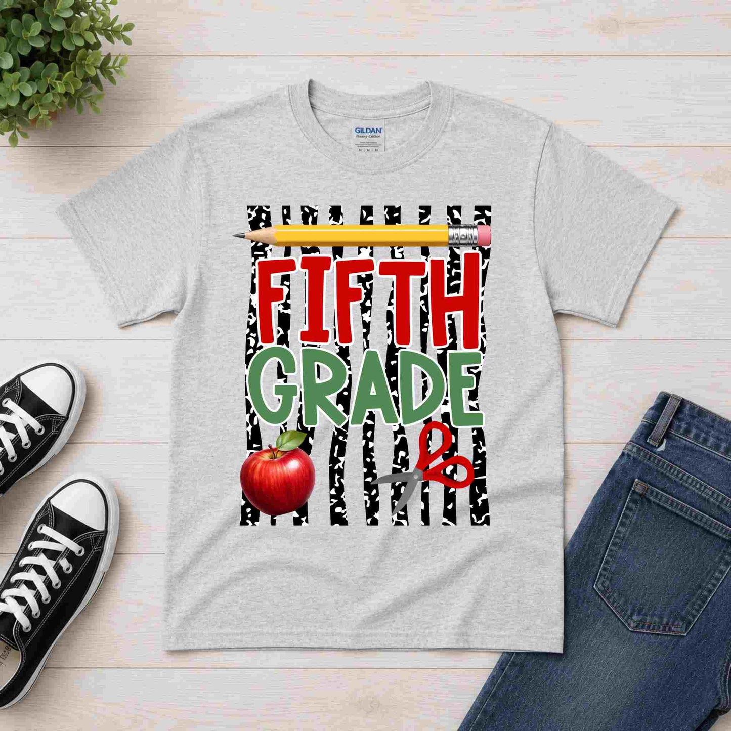 Gray t-shirt with 'Fifth Grade' design on a wooden surface with shoes and jeans.