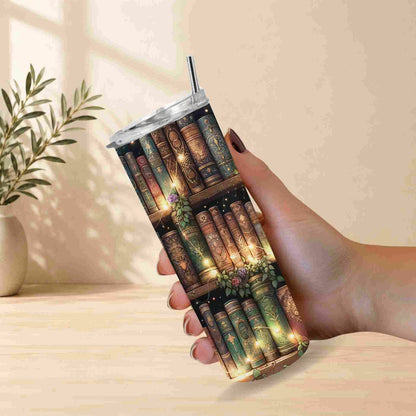 Tumbler with book design held by a hand on a light wooden surface.