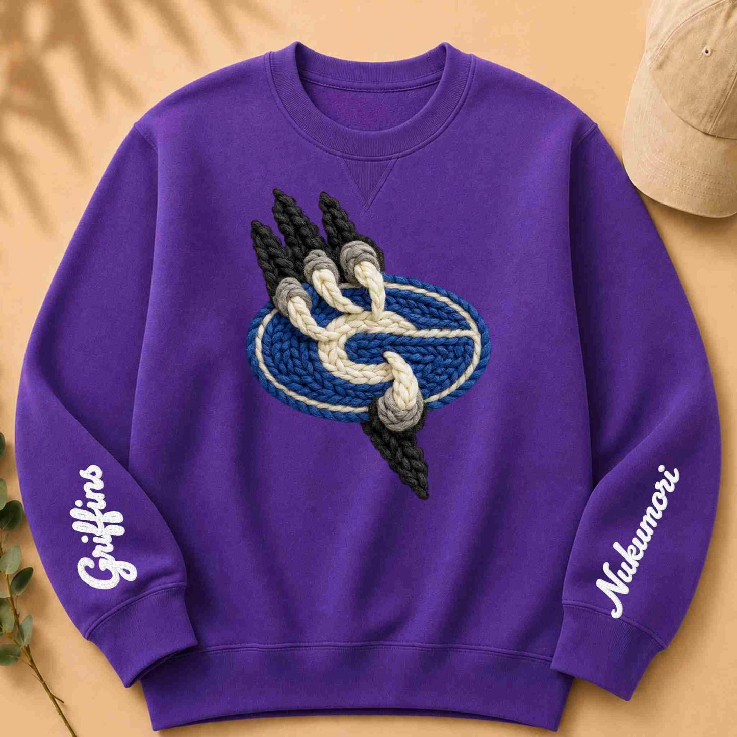 Purple sweatshirt with embroidered design and text on a beige background