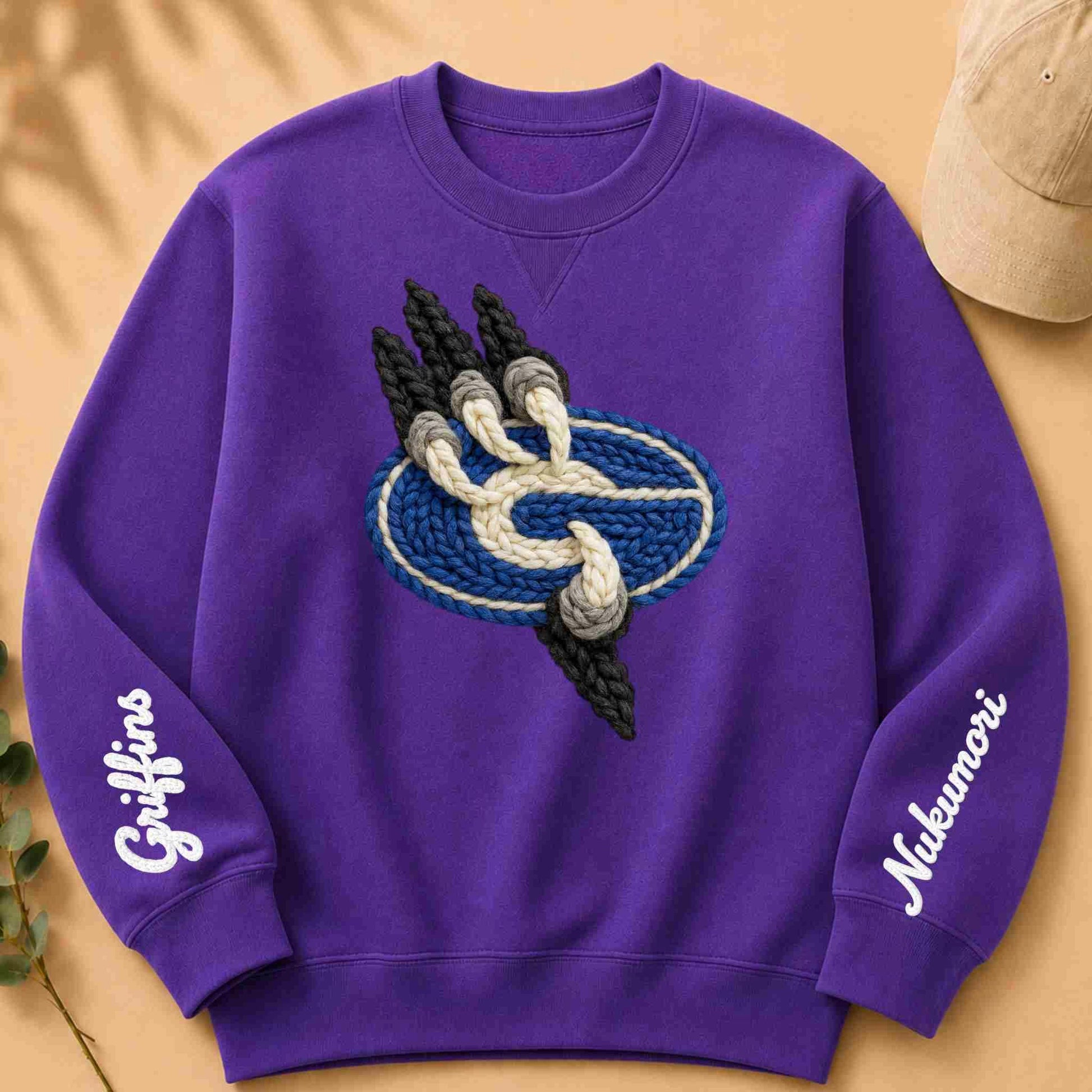 Purple sweatshirt with embroidered design and text on a beige background