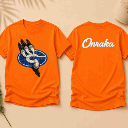 Orange t-shirt with a graphic on the front and 'Onraka' text on the back, displayed on a beige surface.