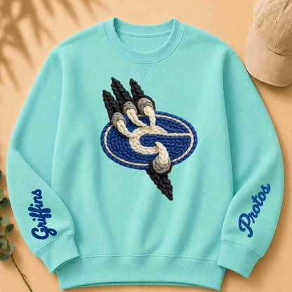 Light blue sweatshirt with embroidered design and 'Griffins' text on a beige surface