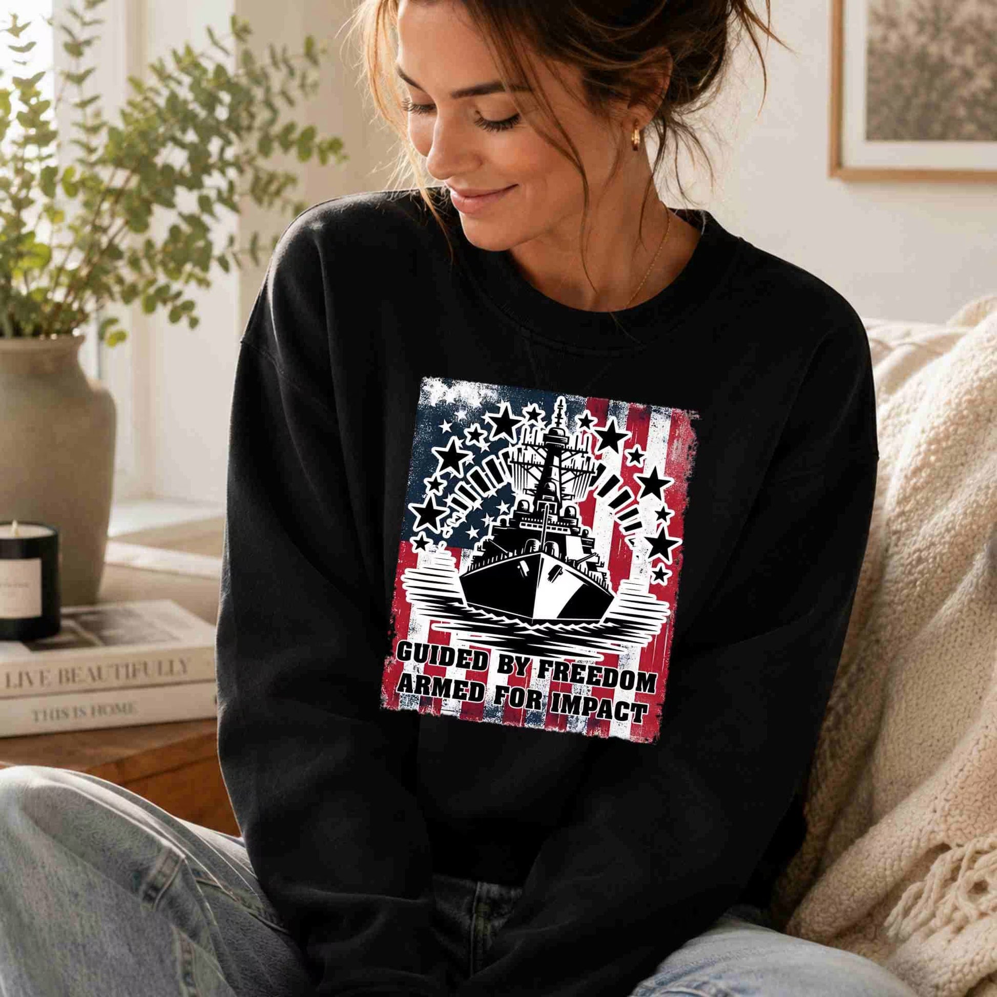 Woman wearing a black sweatshirt with a graphic design sitting on a couch.
