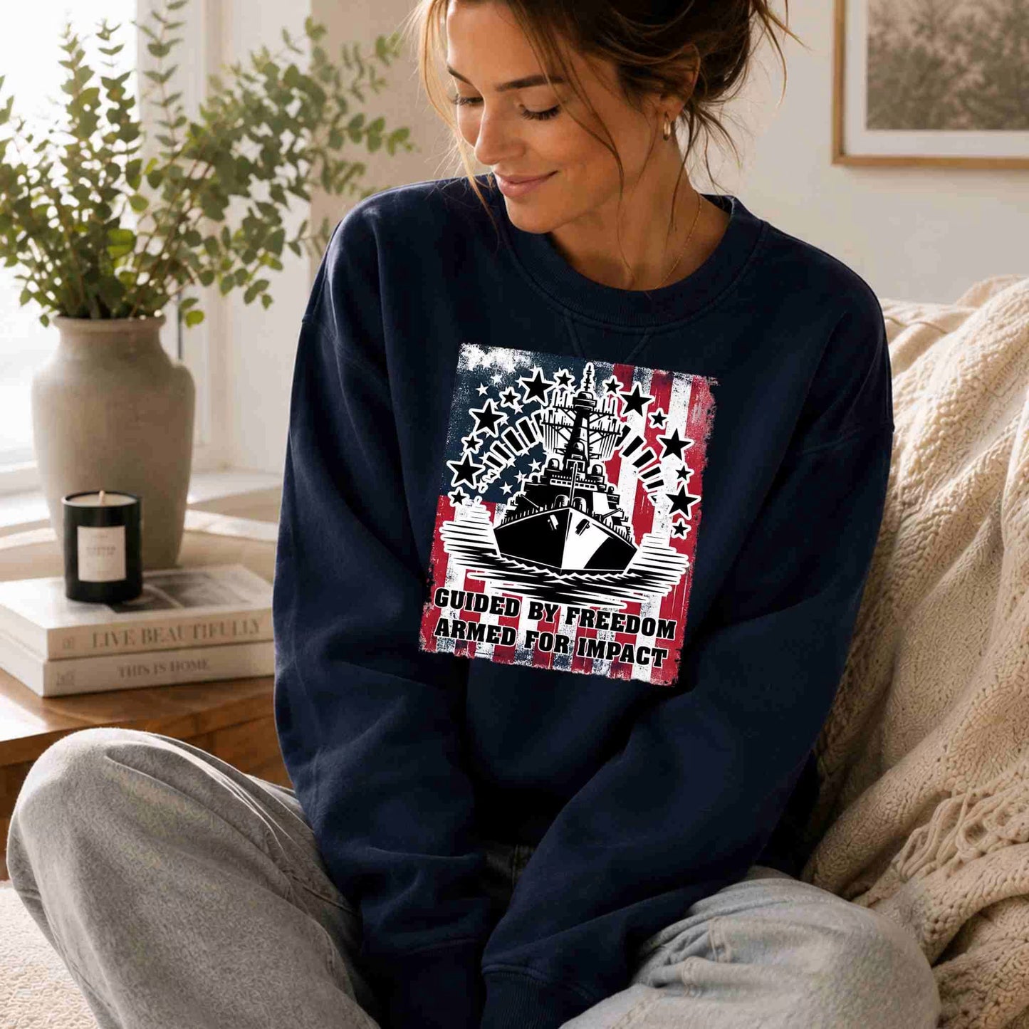 Woman wearing a navy blue sweatshirt with a graphic design, sitting on a couch in a cozy living room.