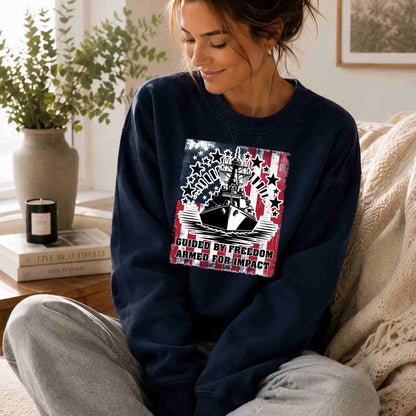 Woman wearing a navy blue sweatshirt with a graphic design, sitting on a couch in a cozy living room.