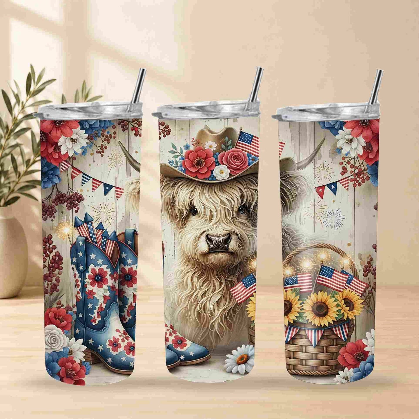 Three stainless steel tumblers with a decorative design featuring a cow, flowers, and American flags on a wooden surface.