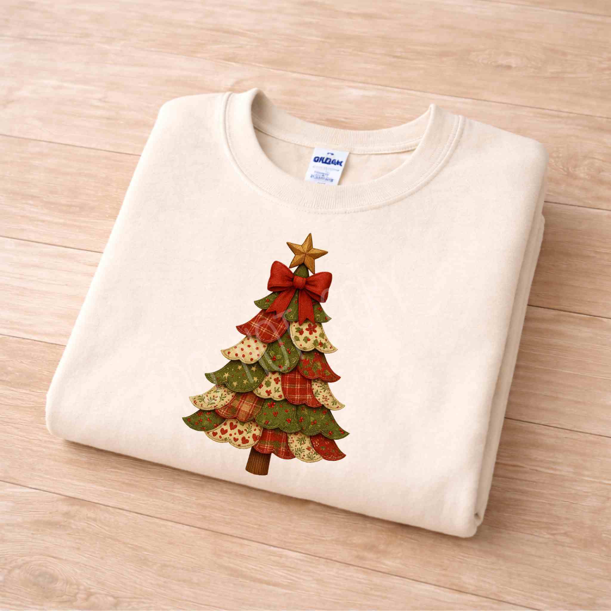 Patchwork Christmas Tree Sweatshirt folded on wooden surface with festive tree design and red bow.