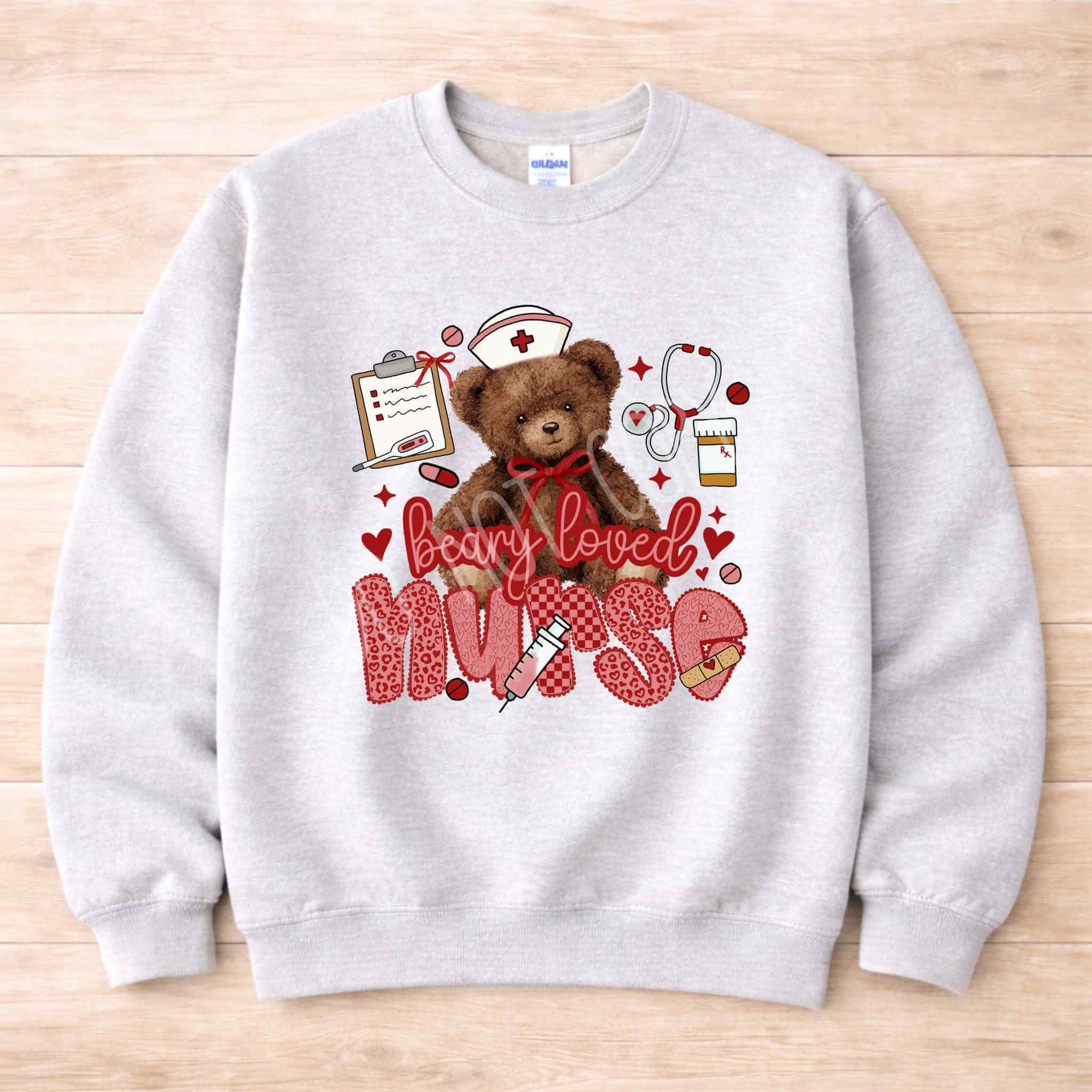 Beary Loved Nurse Sweatshirt Comfort Style and Care featuring a cute teddy bear and nurse-themed icons.