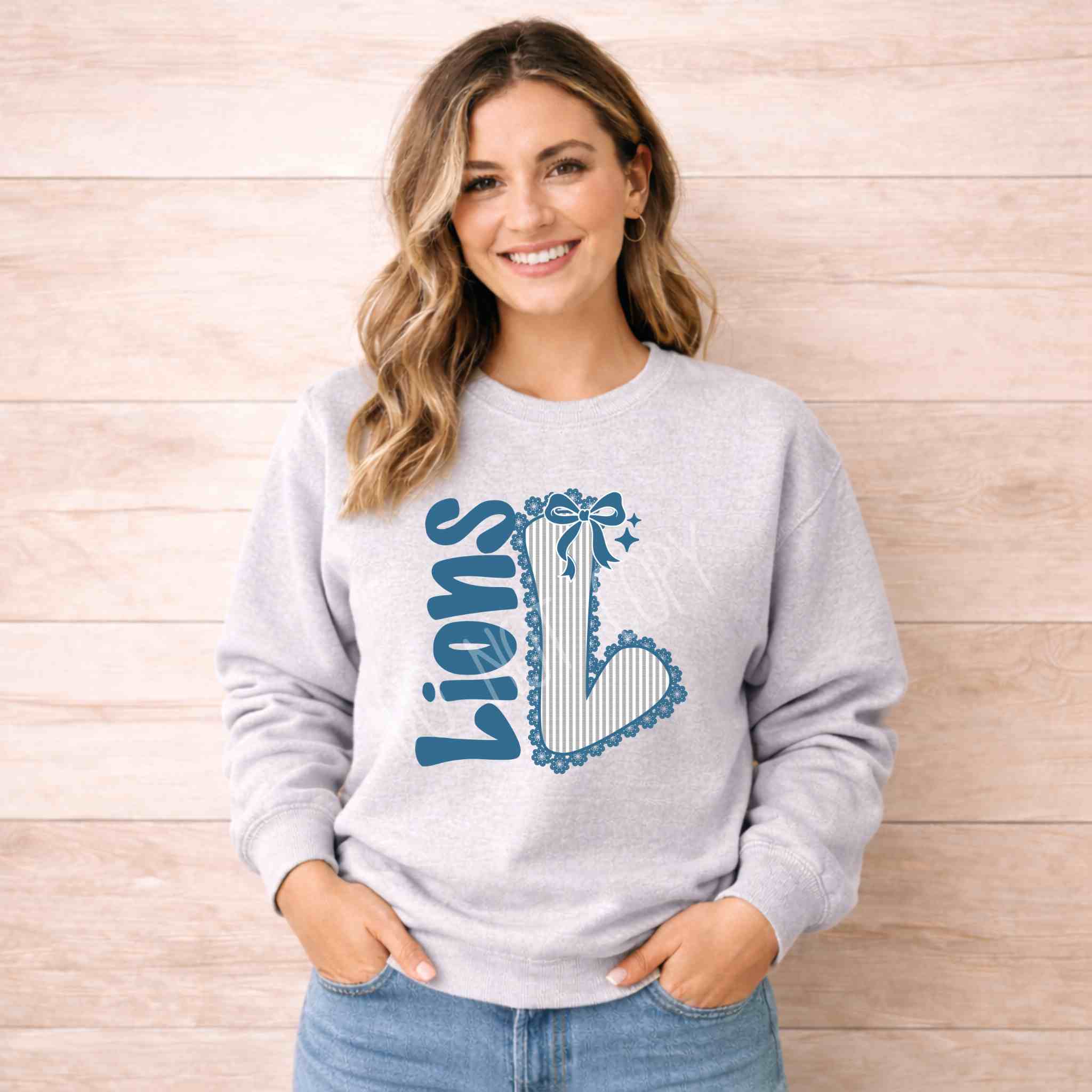 Lions School Spirit Sweatshirt worn by a smiling woman with a bow and varsity 'L' design on a cozy gray crewneck.