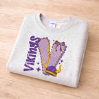 Vikings School Spirit Sweatshirt featuring purple varsity lettering and feminine bow detail on a gray background.