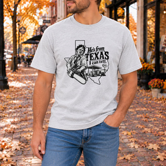Light gray crew-neck horror graphic T-shirt with "He's from TEXAS" text and illustration